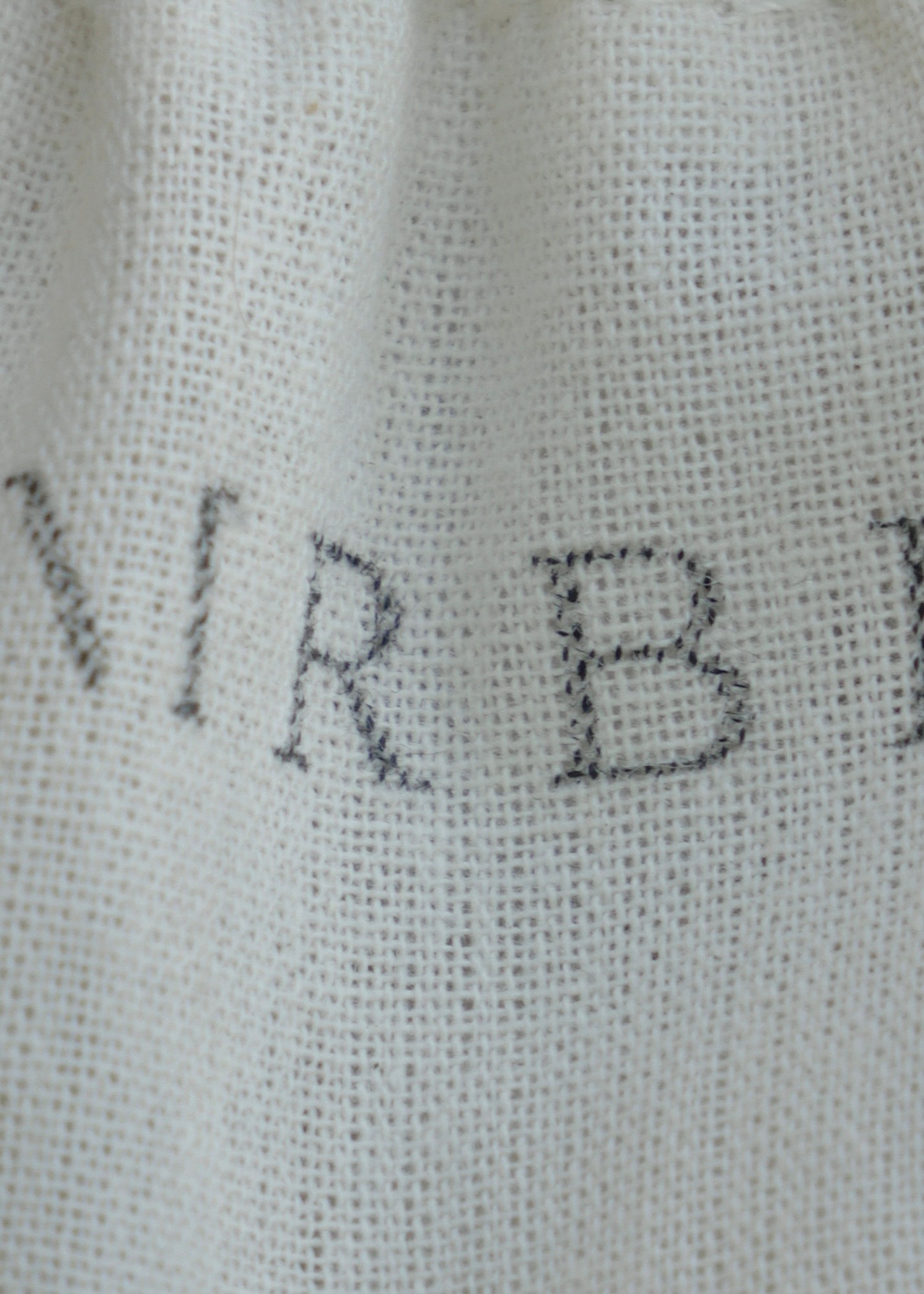 Close-up of fabric with partially visible embroidered text, showing the letters 'NIR B'.