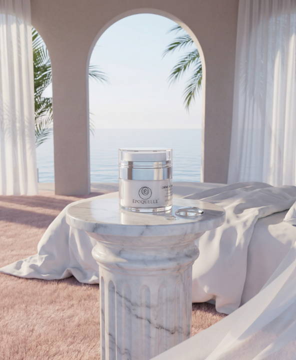 A candle on a marble pedestal in a bright room with an ocean view through an arched window, white curtains, and draped fabric.