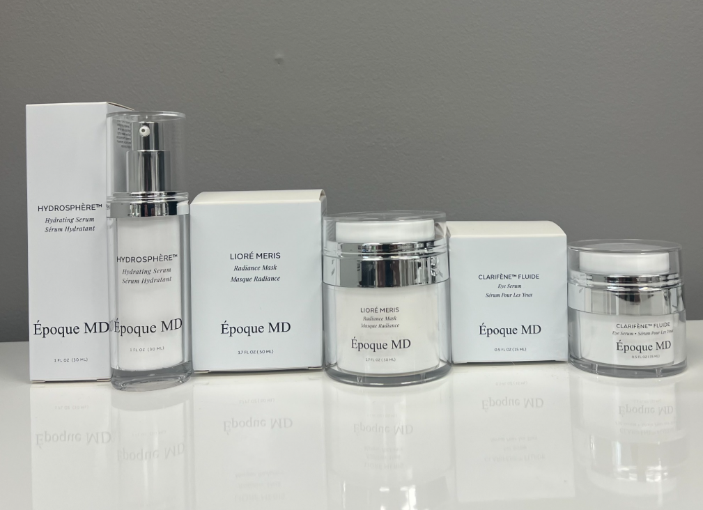 Six skincare product containers and boxes arranged in a row on a white surface against a gray background.