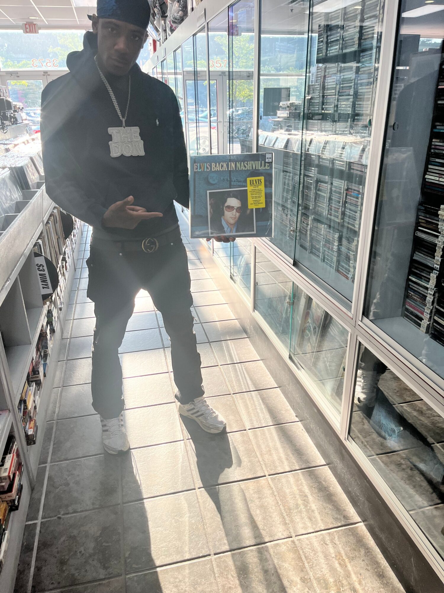A person stands in a glass-walled indoor space beside a display case and tiled floor.