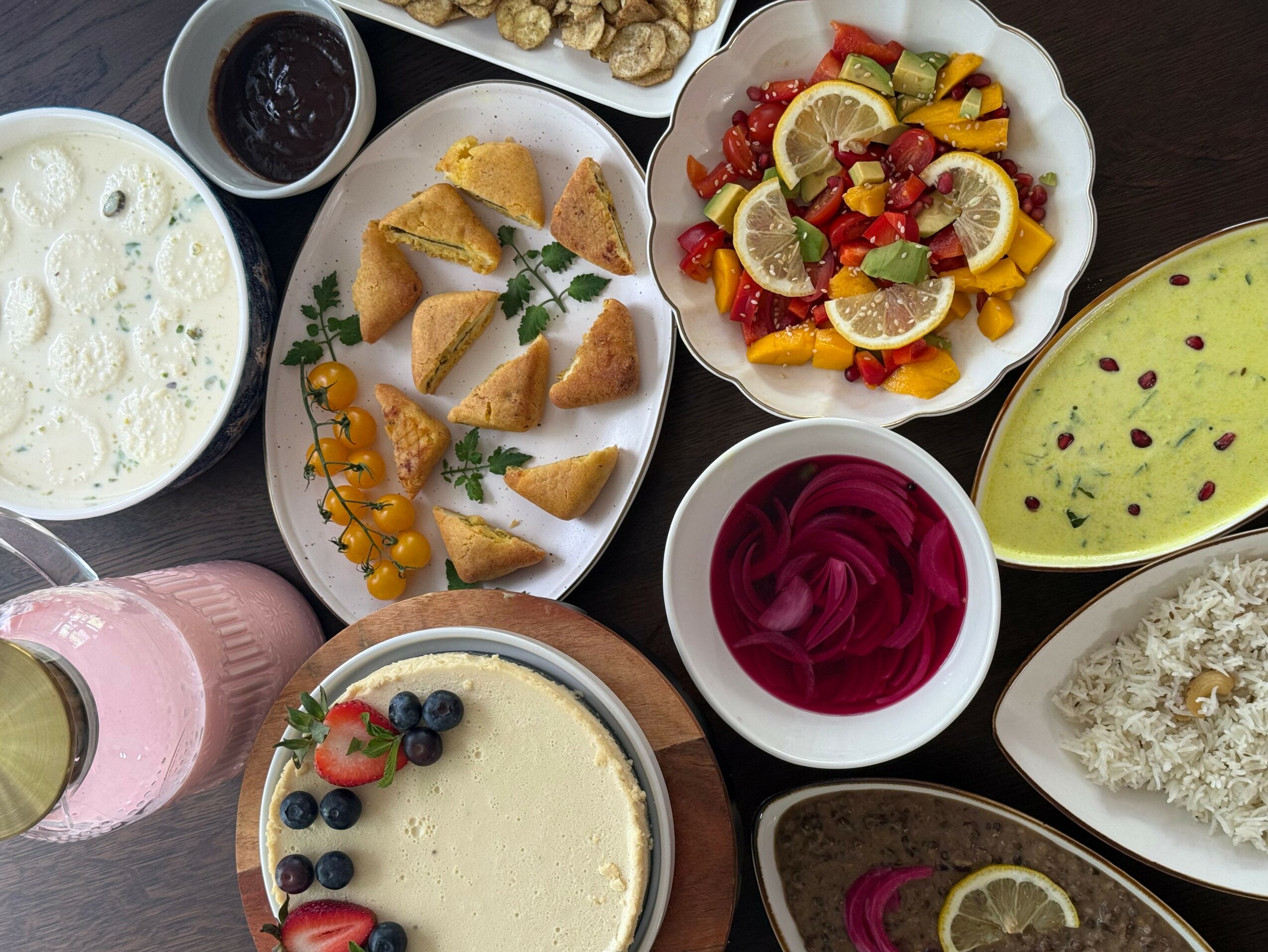 Assorted dishes including fruit salad, rice, curry, and beverages on a table.
