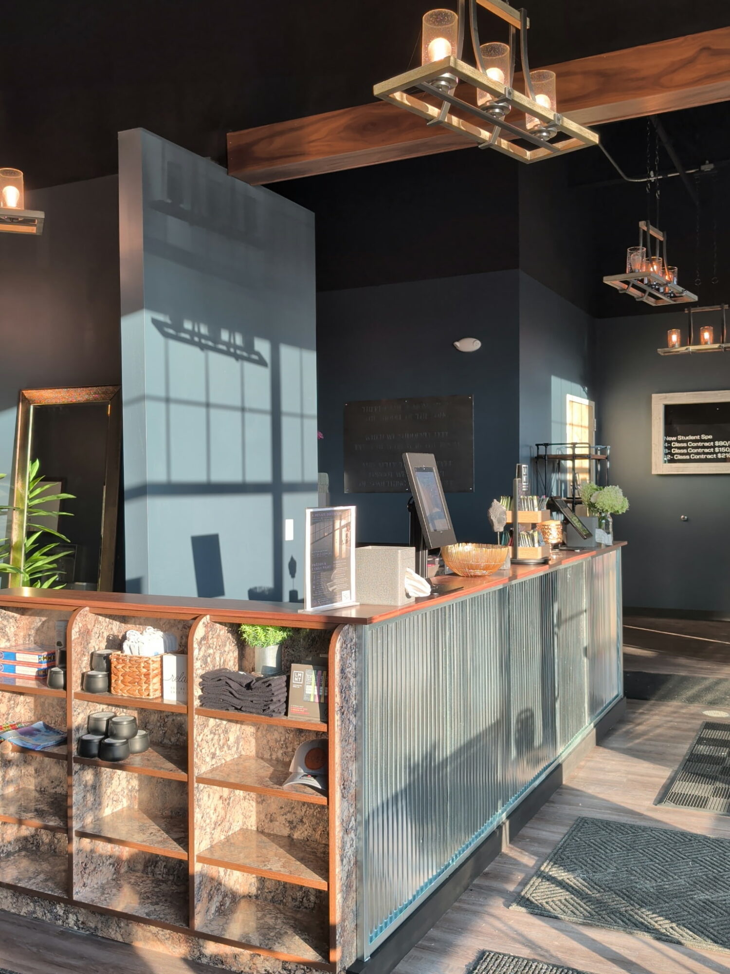 Counter service counter with shelves, a cash register, and decorative plants in a modern cafe interior.