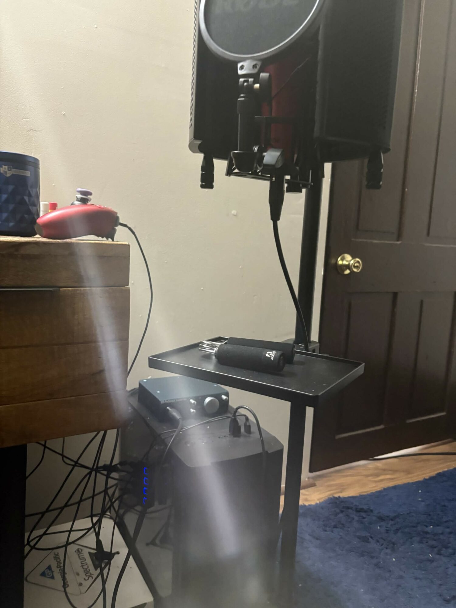 Speaker setup on a stand next to a closed door, with a wooden table and various objects nearby.