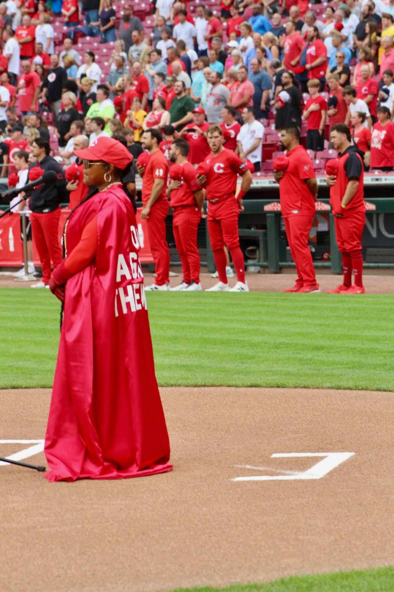 People in red uniforms and a crowd in the background at a sports event, with a person in the foreground holding a flag.