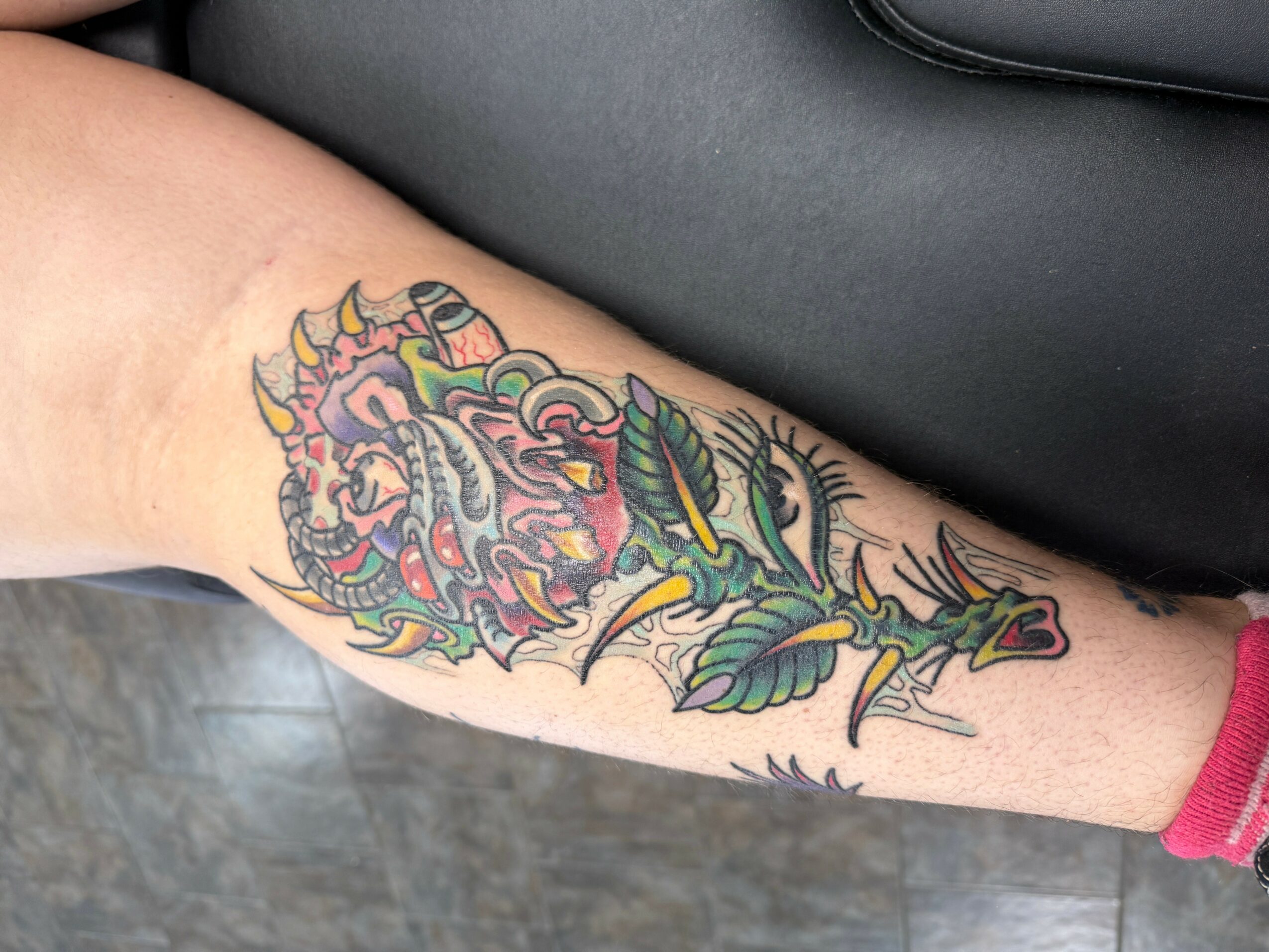 Colorful dragon tattoo on person's forearm with detailed scales and claws.