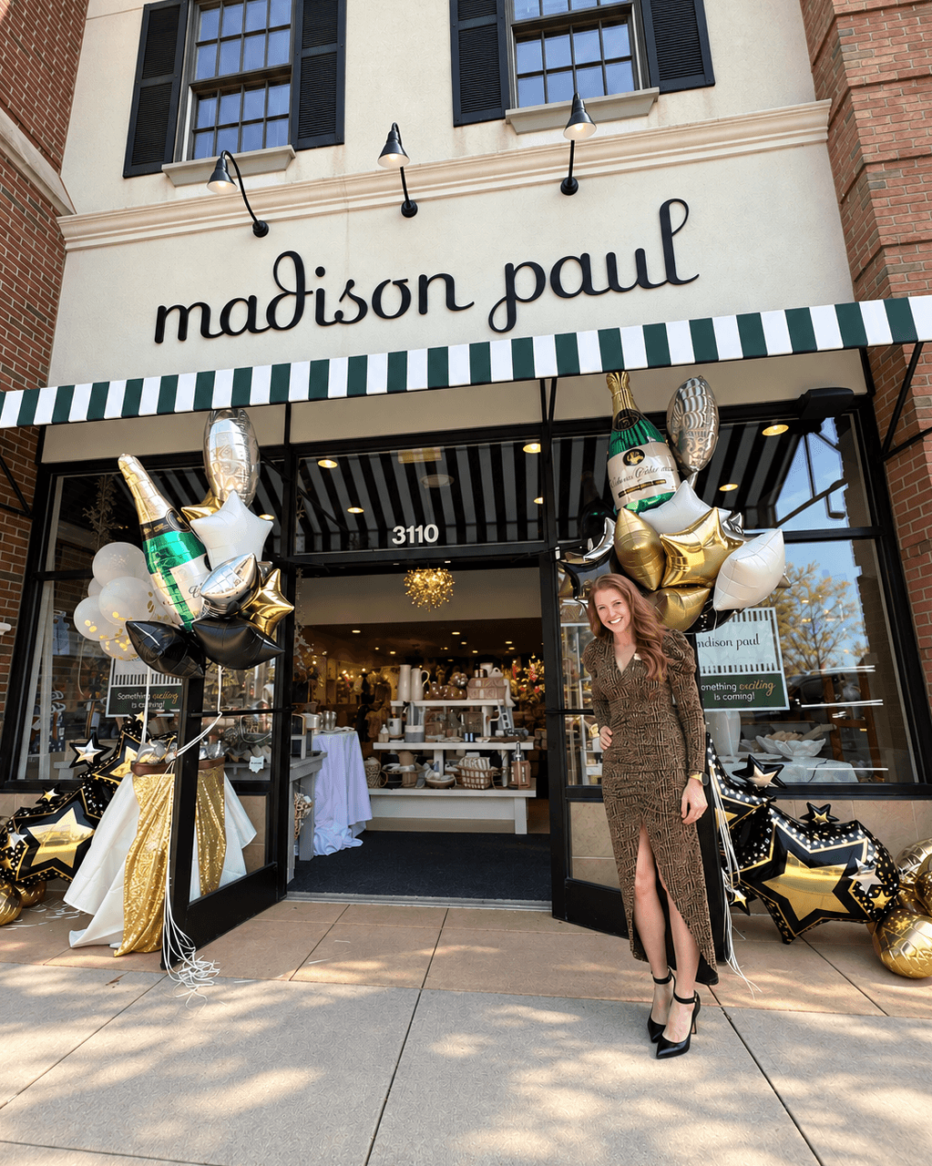 Storefront with “madison paul” sign, decorative balloons, and a person standing near the entrance.