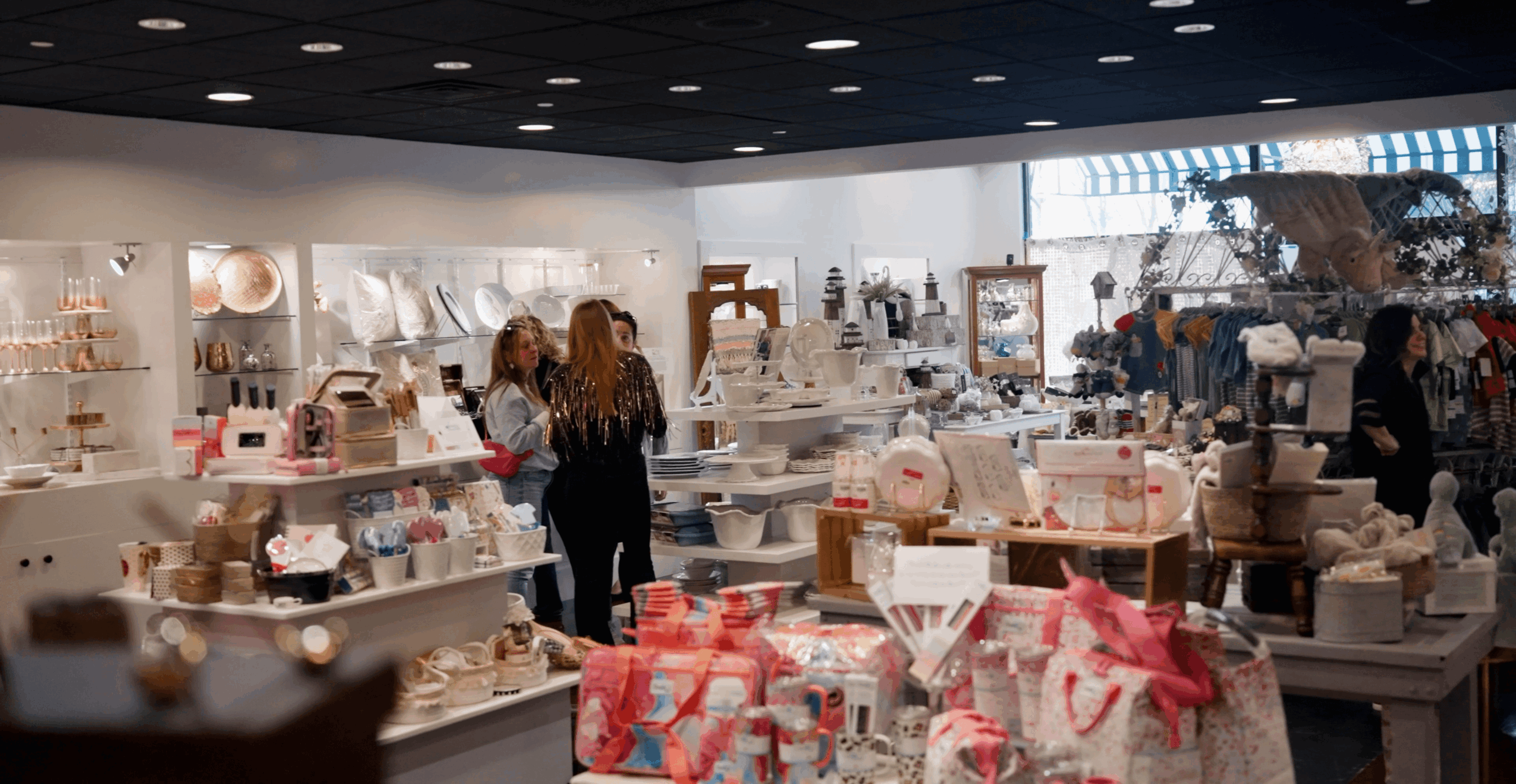 People browse displays of home goods and gift items in a brightly lit store.