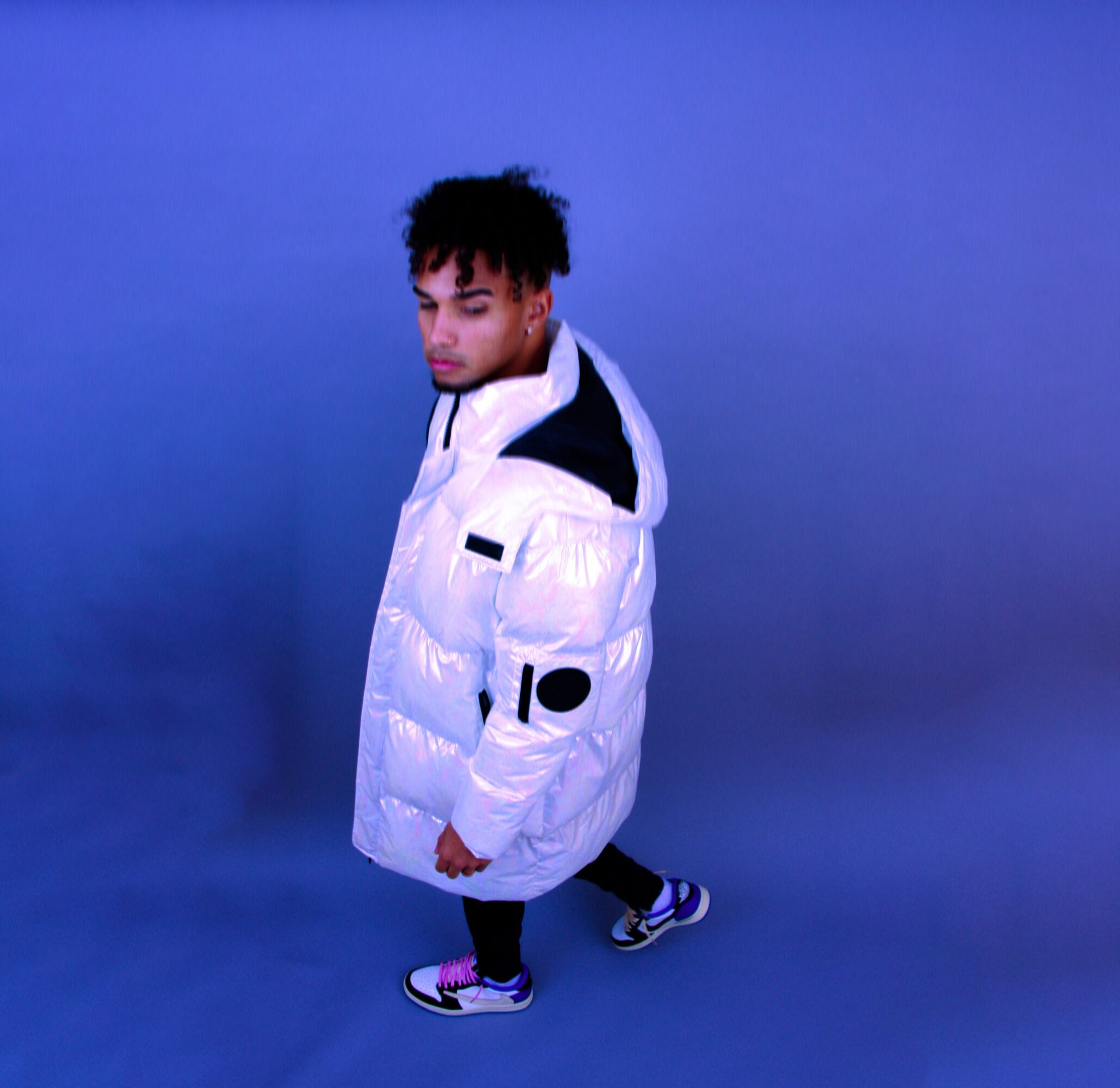 Person in a white puffer jacket standing against a blue background.