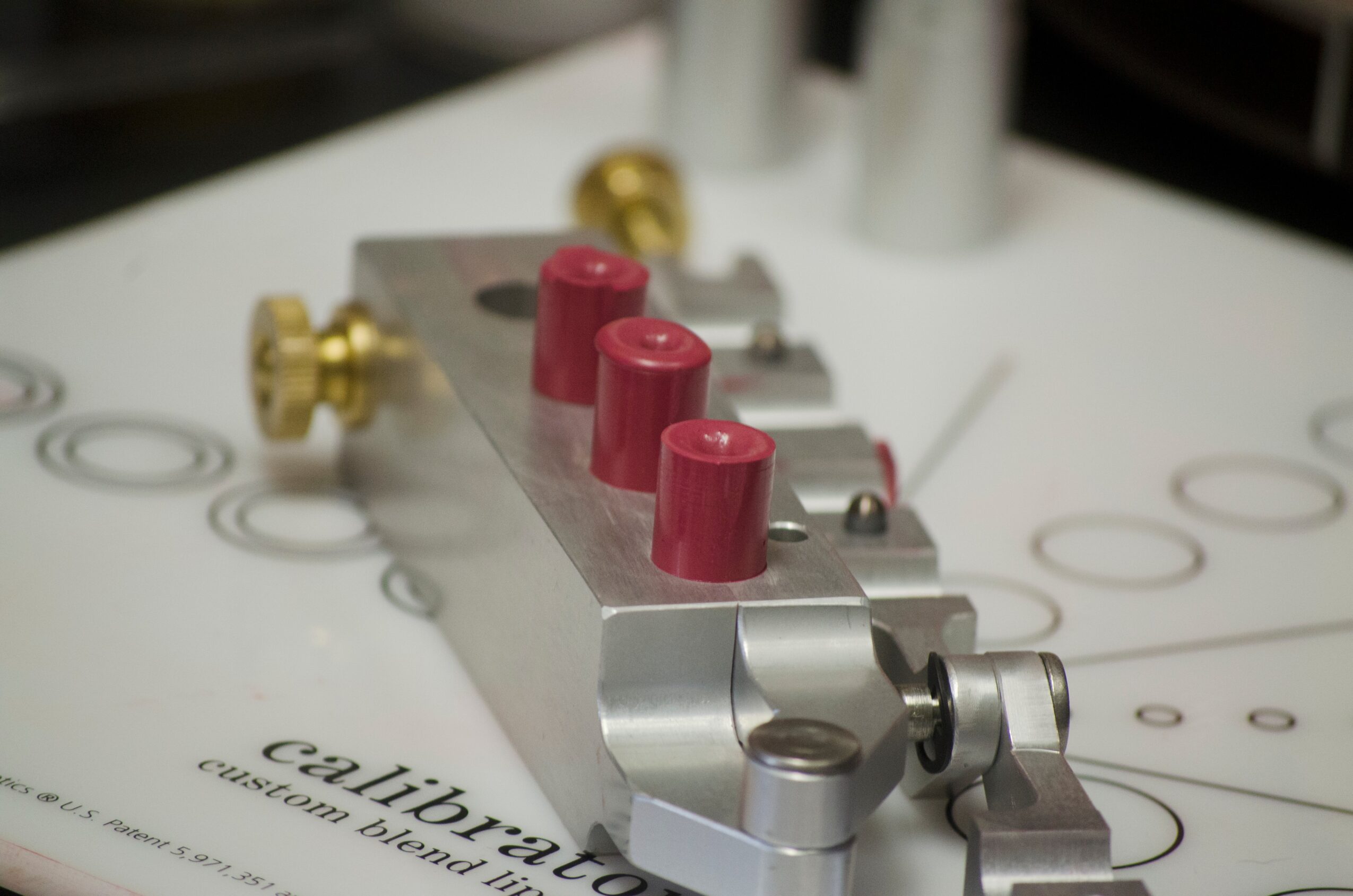 Metal calibration fixture with red posts rests on a printed measurement surface.