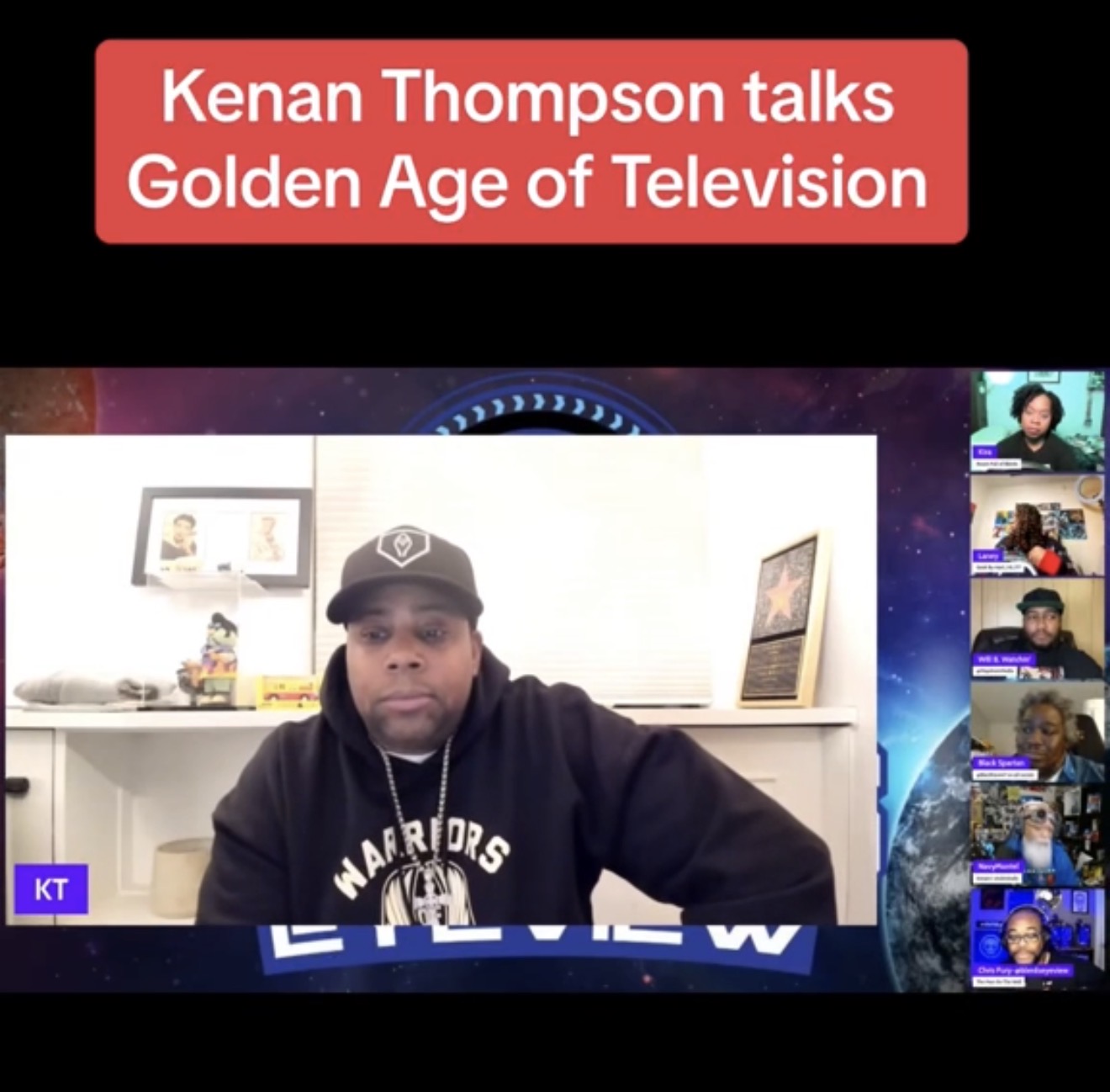 Person wearing a cap and hoodie, sitting at a desk during a virtual meeting, with a red banner above reading 'Kenan Thompson talks Golden Age of Television'.