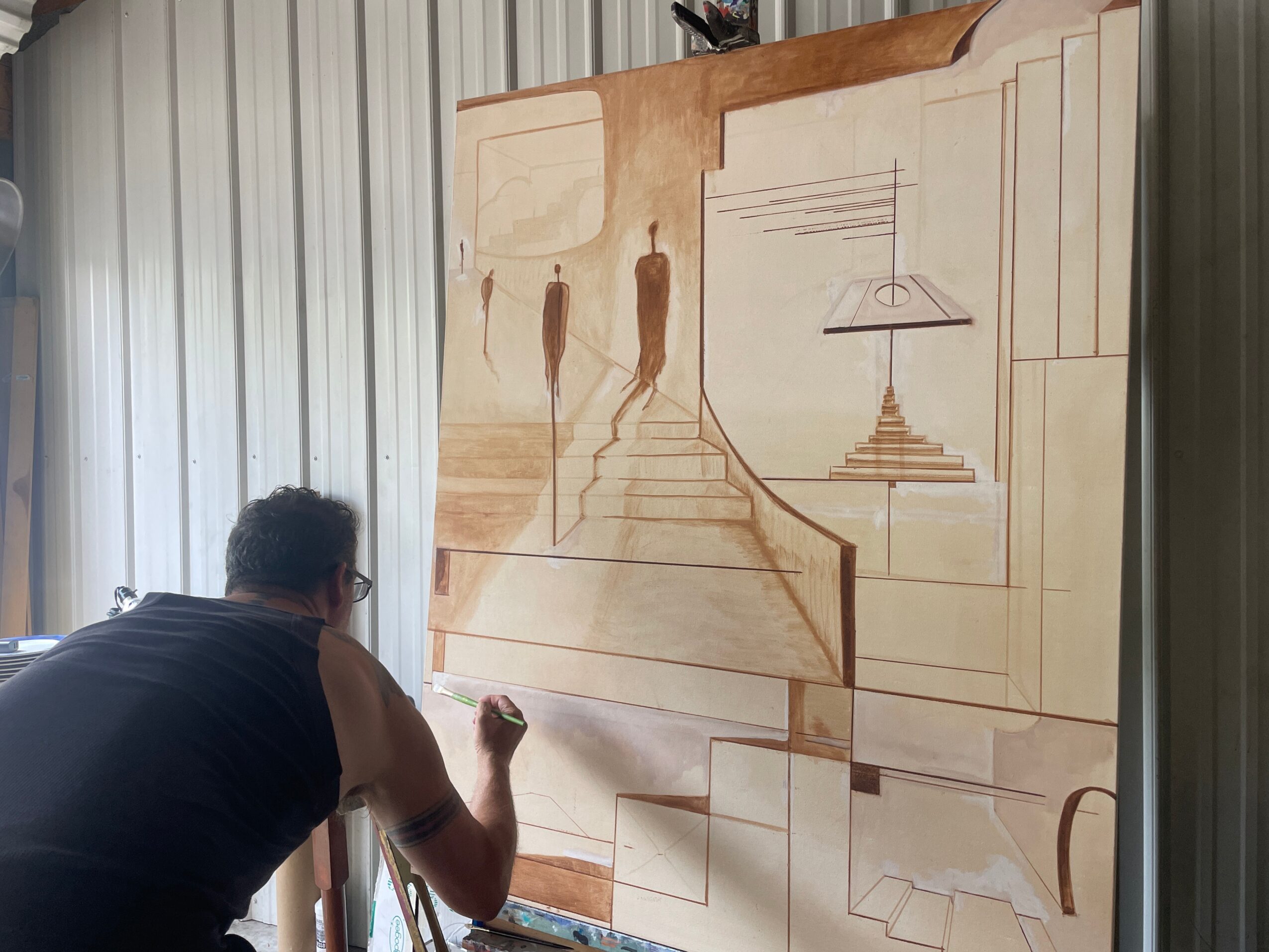 Person paints a large architectural mural on a wall in a workshop.
